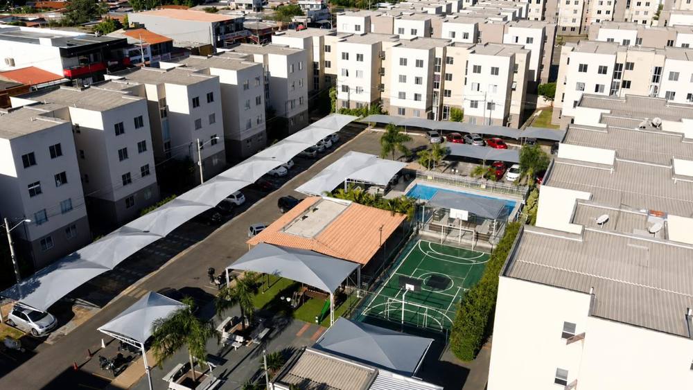 Vista aérea de condomínio com piscina, quadra e garagens cobertas